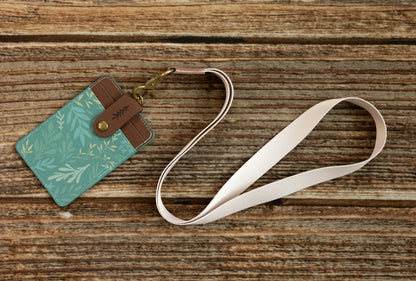 Tan Neck Lanyard attached to a teal botanical print ID card holder on a wood surface