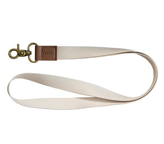 Tan Neck Lanyard laid flat on a white background, showing the cream strap, brown vegan leather patch, and bronze swivel hook