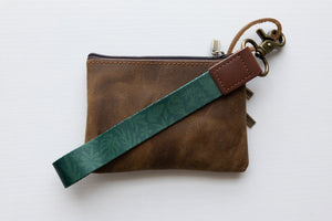 Tropical printed green wristlet keychain with brown leather ends and bronze hook attached to brown coin pouch