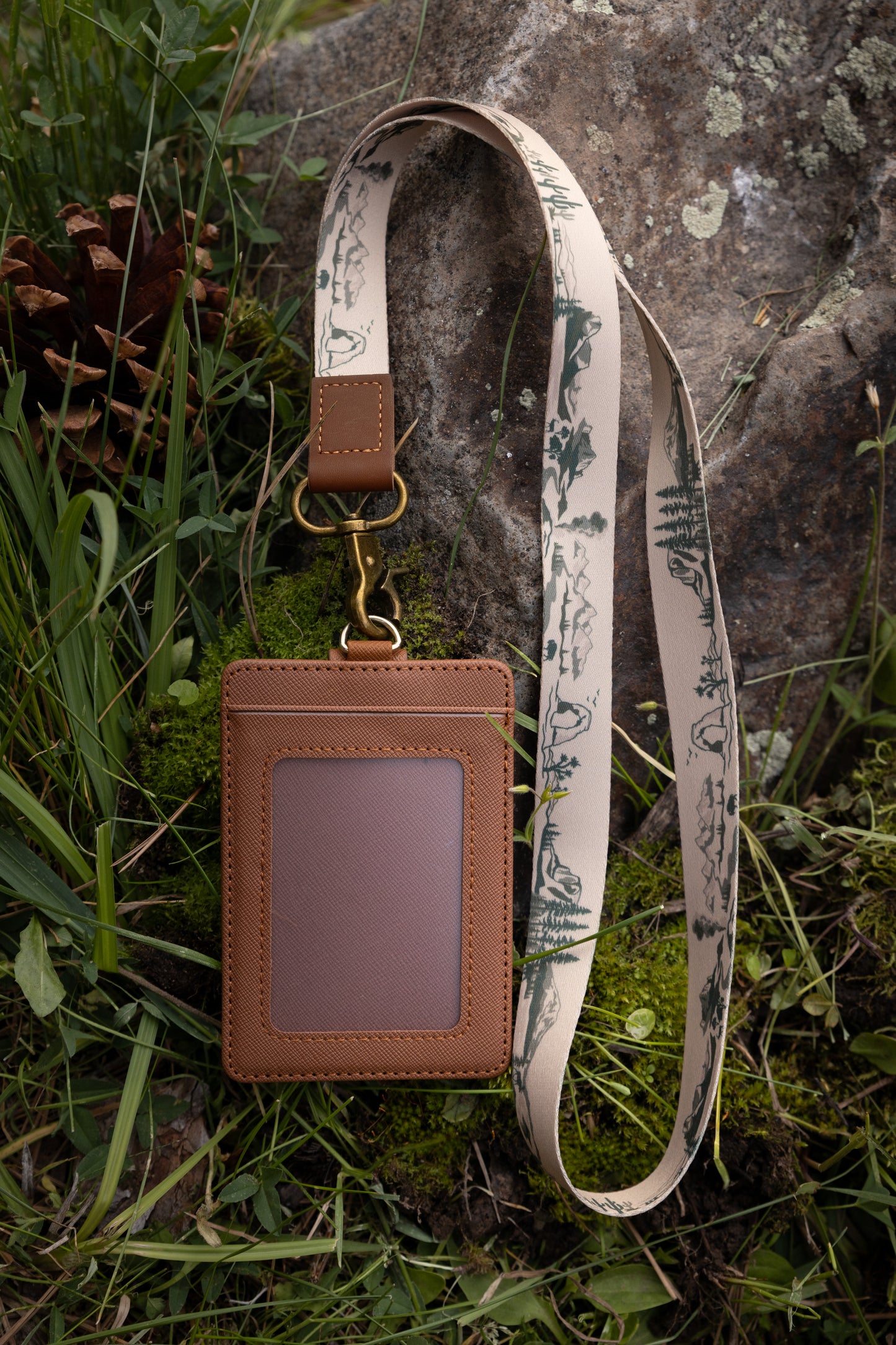 National park printed neck lanyard connected to id holder laying on forest floor