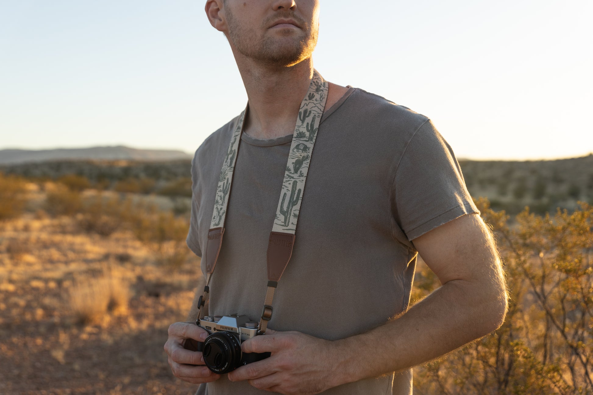 Western landscape camera strap worn around mans neck