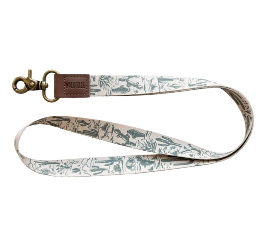 Western landscape neck lanyard by Wildtree, showcasing a pattern of green cacti and desert flora on a light background.