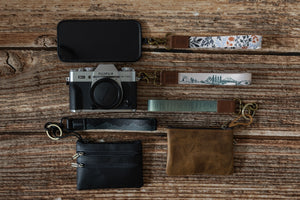 Assortment of personal items with wildtree keychains attached. personal items are phone, camera, wallet and coin pouch