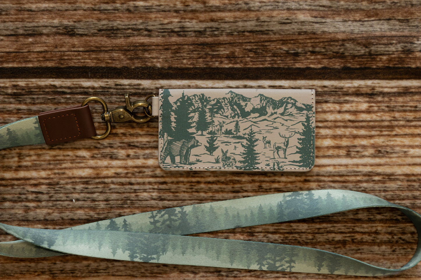 A WILDTREE woodland SD card holder attached to a matching foggy forest neck lanyard via a brass-colored metal swivel clip.