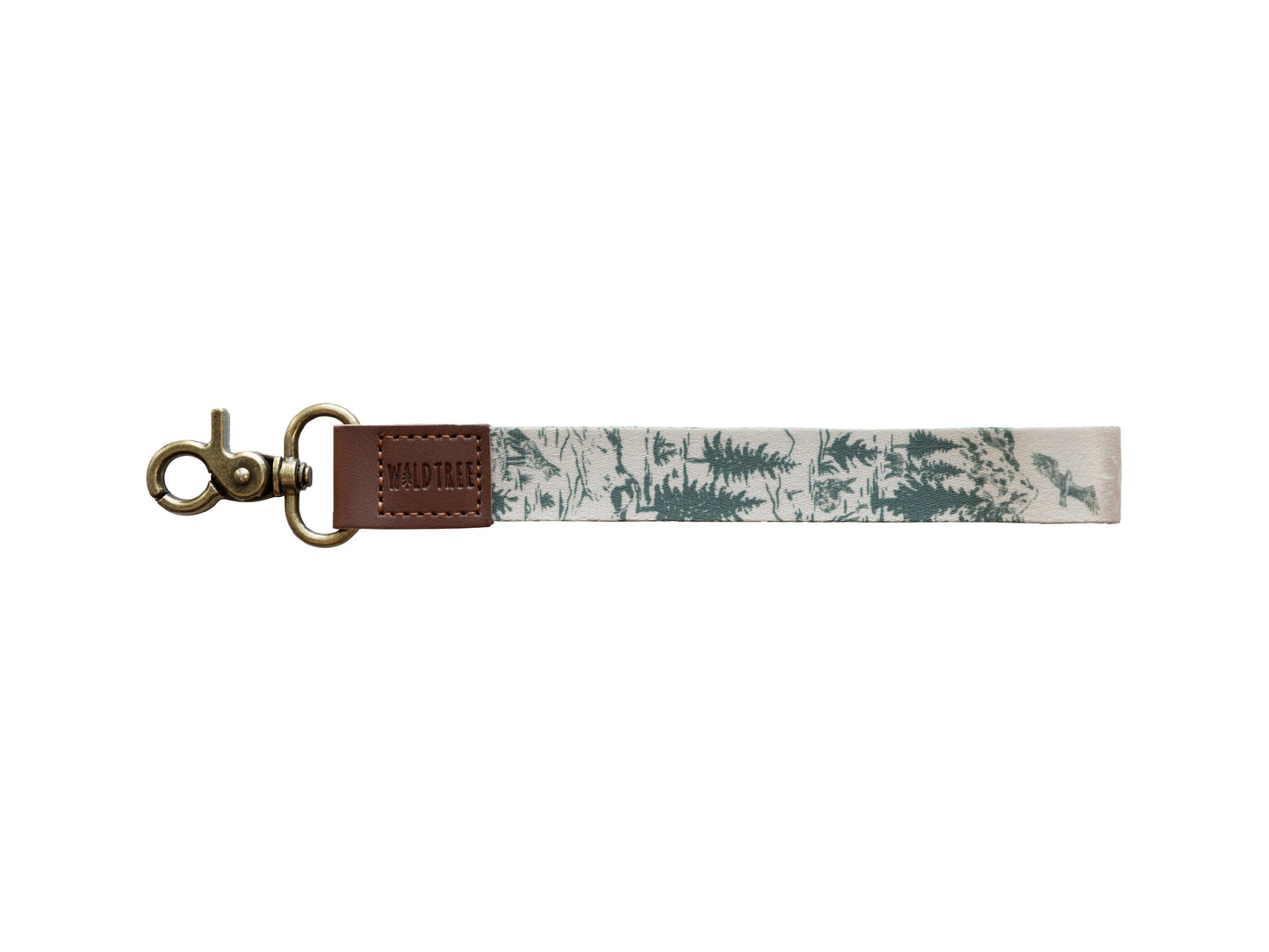 A clean product studio shot of the Woodland Landscape wristlet keychain isolated on a white background. The design features a hand-drawn forest pattern with evergreens and a soaring eagle, attached to a brown vegan leather tab embossed with the WILDTREE logo and a bronze antique-style swivel hook.