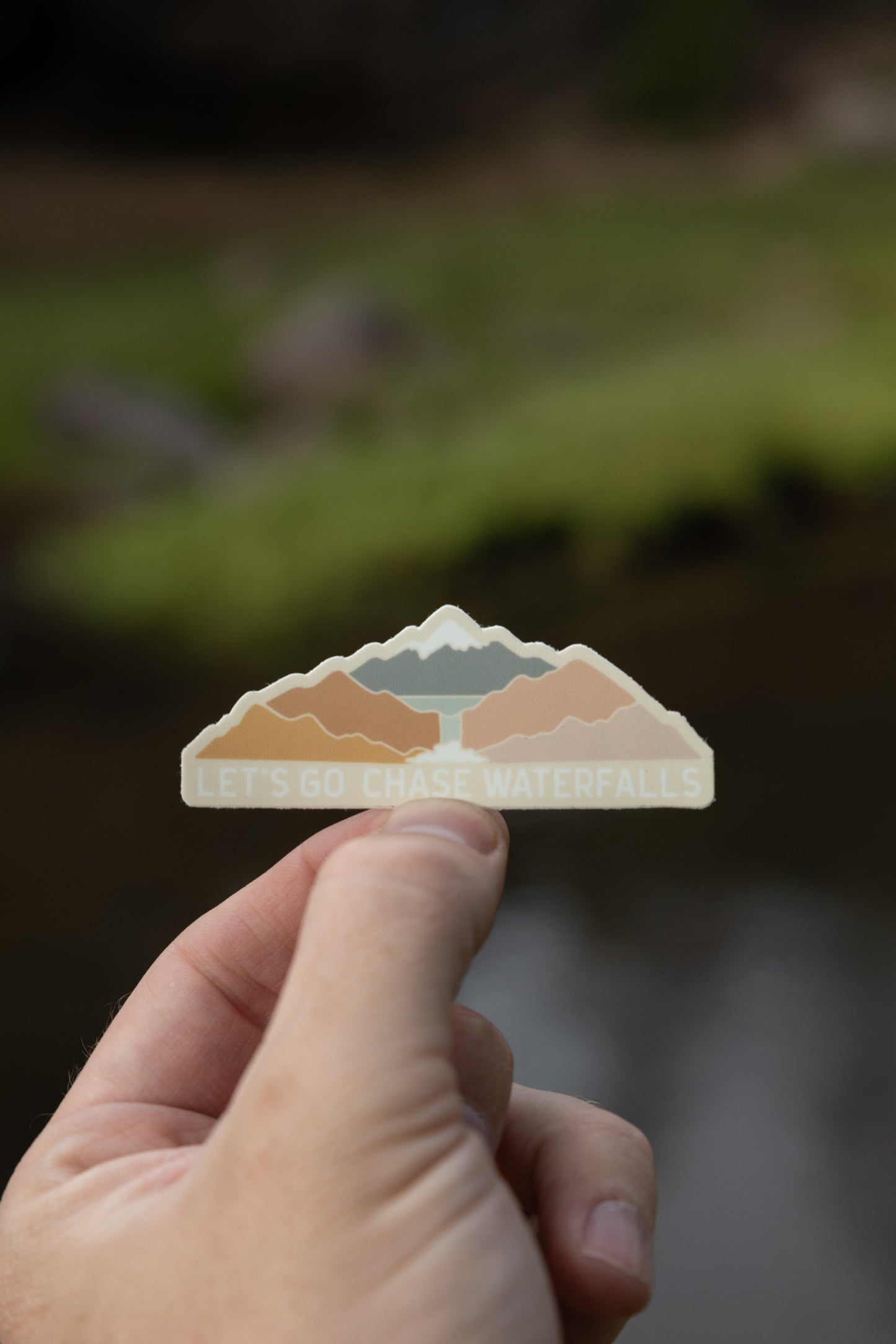 sticker design featuring colorful mountains and a waterfall with the words "Let's Go Chase Waterfalls"