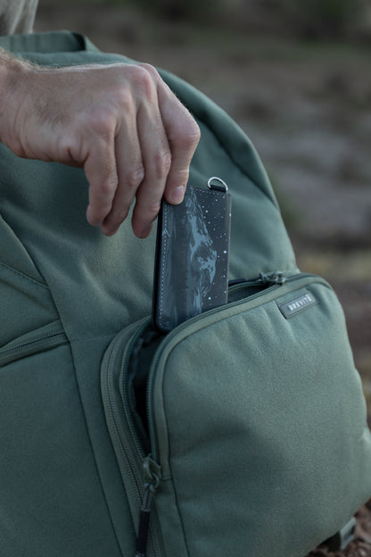 Hand placing the Parks at Night SD card holder into a backpack pocket