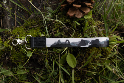 National park printed wristlet keychain in black and white laying on forest floor