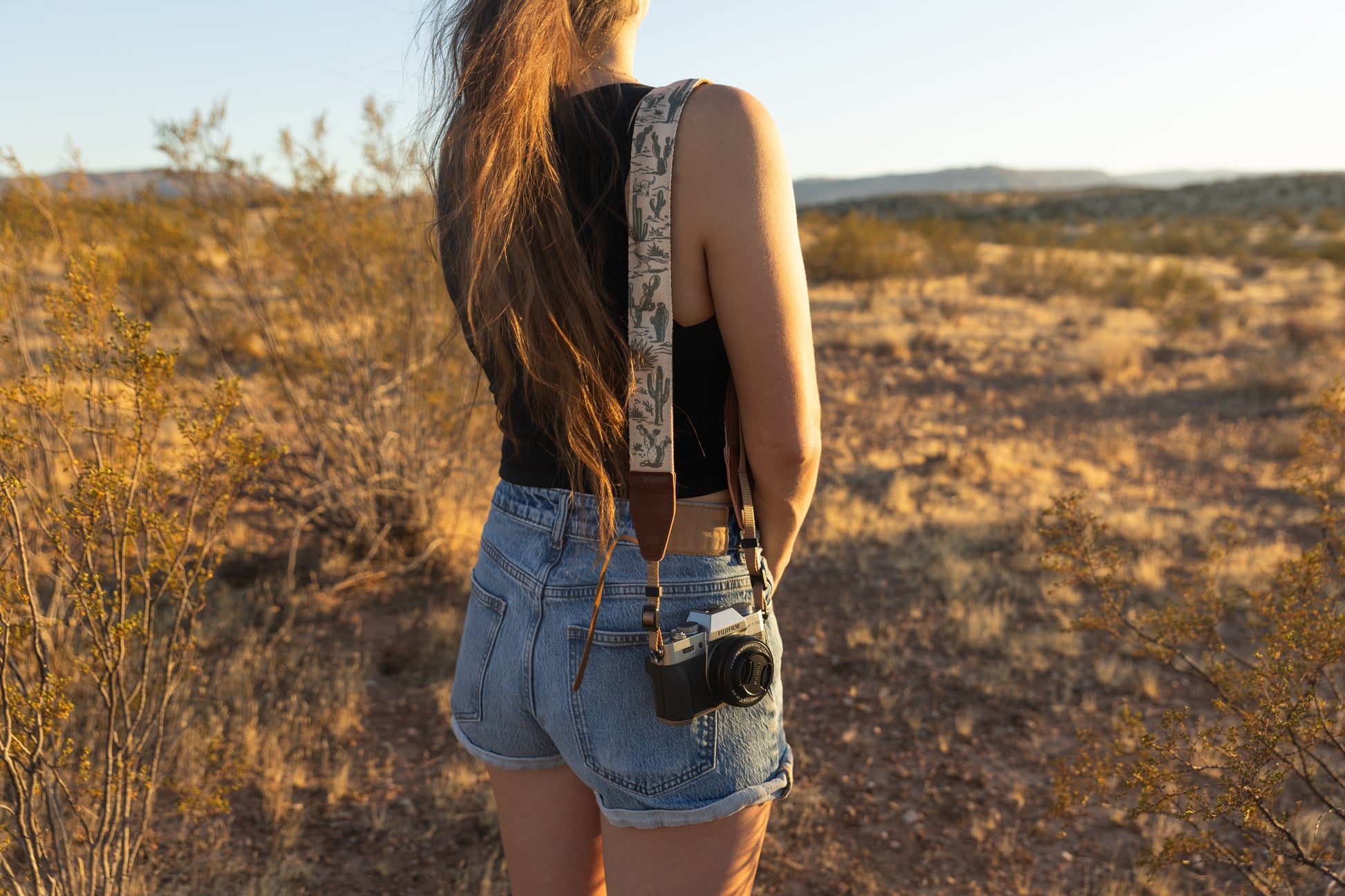 Western landscape camera strap worn over womens shoulder