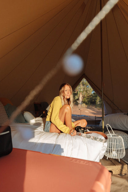 Girl sitting on bed with wildtree moody flower floral print camera strap on shoulder connected to canon camera