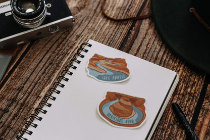 Wildtree Lake Powell Sticker and Horseshoe bend sticker sitting on notepad