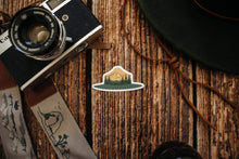 Load image into Gallery viewer, Respect Our Parks Park Ranger Hat Sticker with Trees and Mountains sitting on wood floor surrounded by hat and camera
