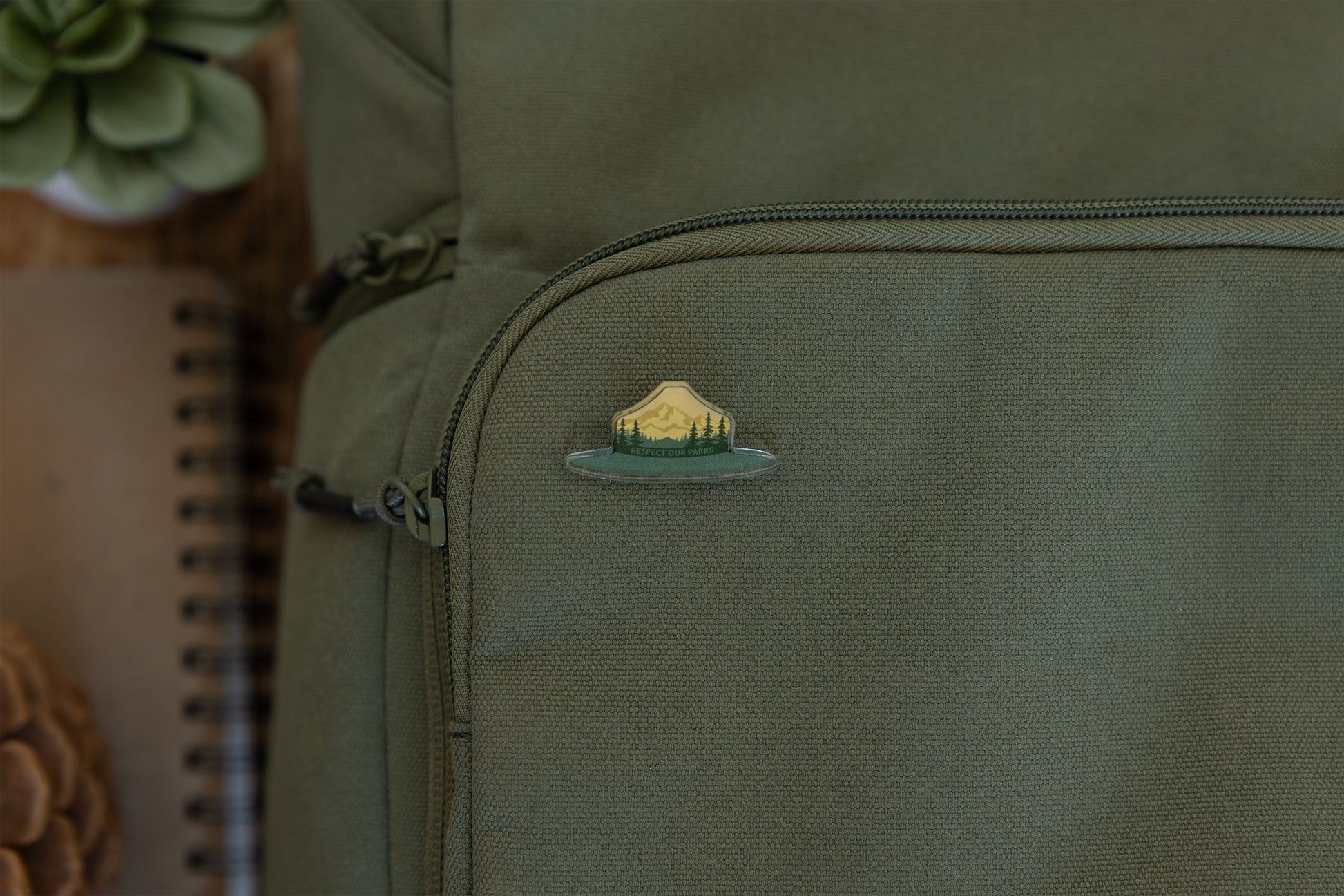 Wildtree park ranger hat pin displaying words "Respect our Parks" pinned to backpack