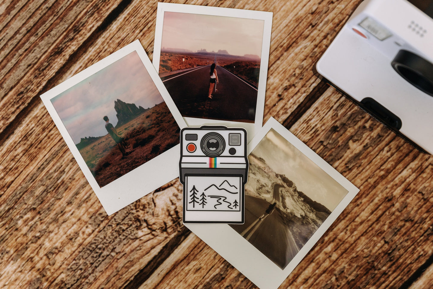 Wildtree Outdoor Photographer Polaroid sticker sitting on wood floor surrounded by polaroid photos