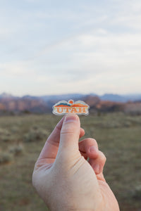 Hand holding up Utah pin
