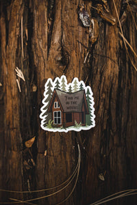 Find me in the woods cabin sticker sitting on log