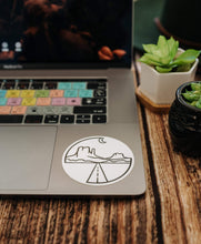 Load image into Gallery viewer, Wildtree Monument Valley Sticker On laptop surrounded by plants
