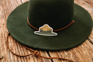 Green and Orange Park Ranger Hat Sticker sitting on Green hat