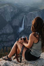 Load image into Gallery viewer, Women sitting overlooking waterfall holding film camera and Wildtree camera strap
