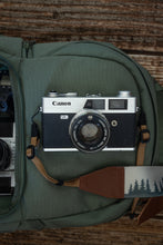 Load image into Gallery viewer, Canon film camera with wildtree strap adapters sitting on backpack 
