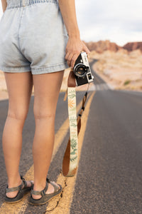 Women holding camera to side with wildtree wild desert camera strap attached