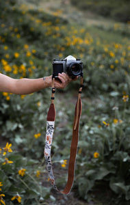 extended hand holding film camera with Wildtree Wildflower Floral camera strap attached