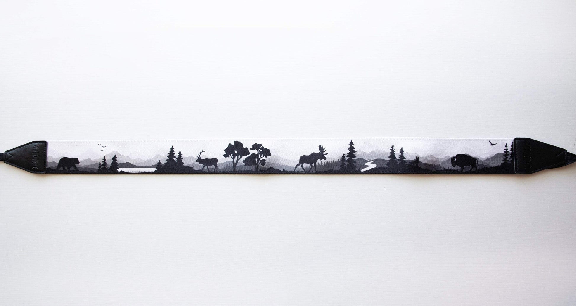 Wildtree Wildlife Camera Strap featuring Bear, Moose, birds and Trees with mountain range background connected to Canon film camera