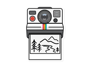 Sticker Graphic of Old Polaroid Camera Ejecting photo with illustration of mountains and trees