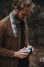 Load image into Gallery viewer, Man holding camera with Wildtree landscape camera strap around neck
