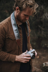 Man holding camera with Wildtree landscape camera strap around neck