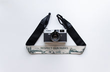 Load image into Gallery viewer, Wildree Respect our parks camera strap with black synthetic leather ends attached to film camera
