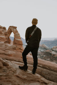Man looking at Delicate Arch in Arches national park wearing National park inspired camera strap