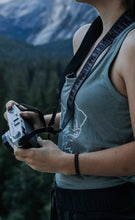 Load image into Gallery viewer, women standing with Wildtree Night Sky Camera Strap holding camera

