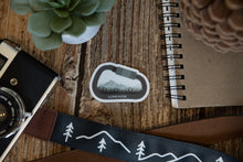 Load image into Gallery viewer, Climb More Carabiner Sticker on wood background surrounded by notebook, camera and succulent 
