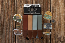 Load image into Gallery viewer, Happy camper wildtree sticker on wood background with other camera strap, stickers and pins
