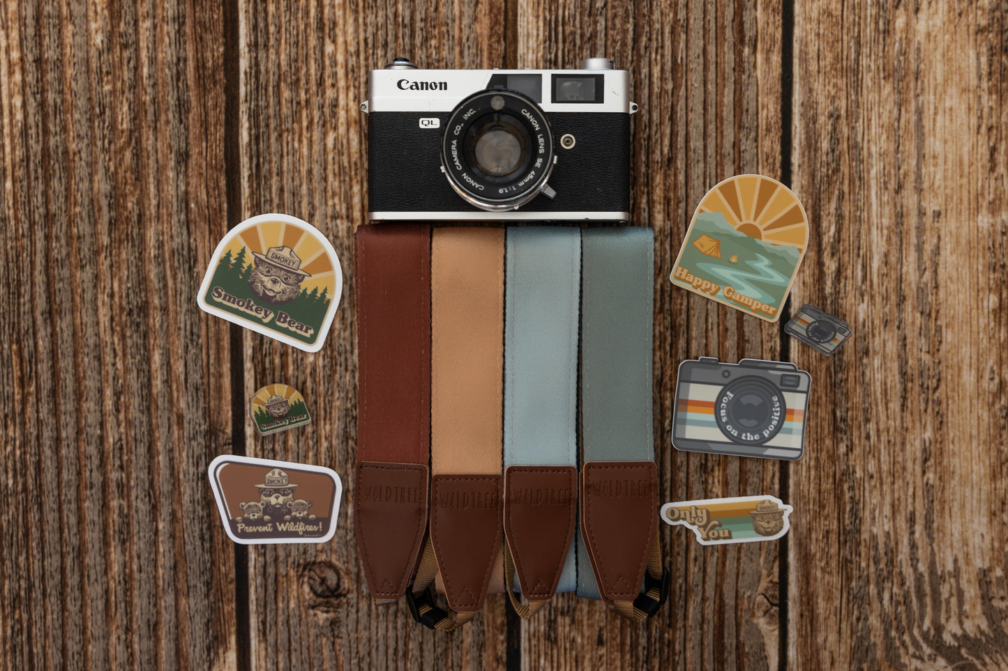 smokey bear sticker on wood background with other camera strap, stickers and pins