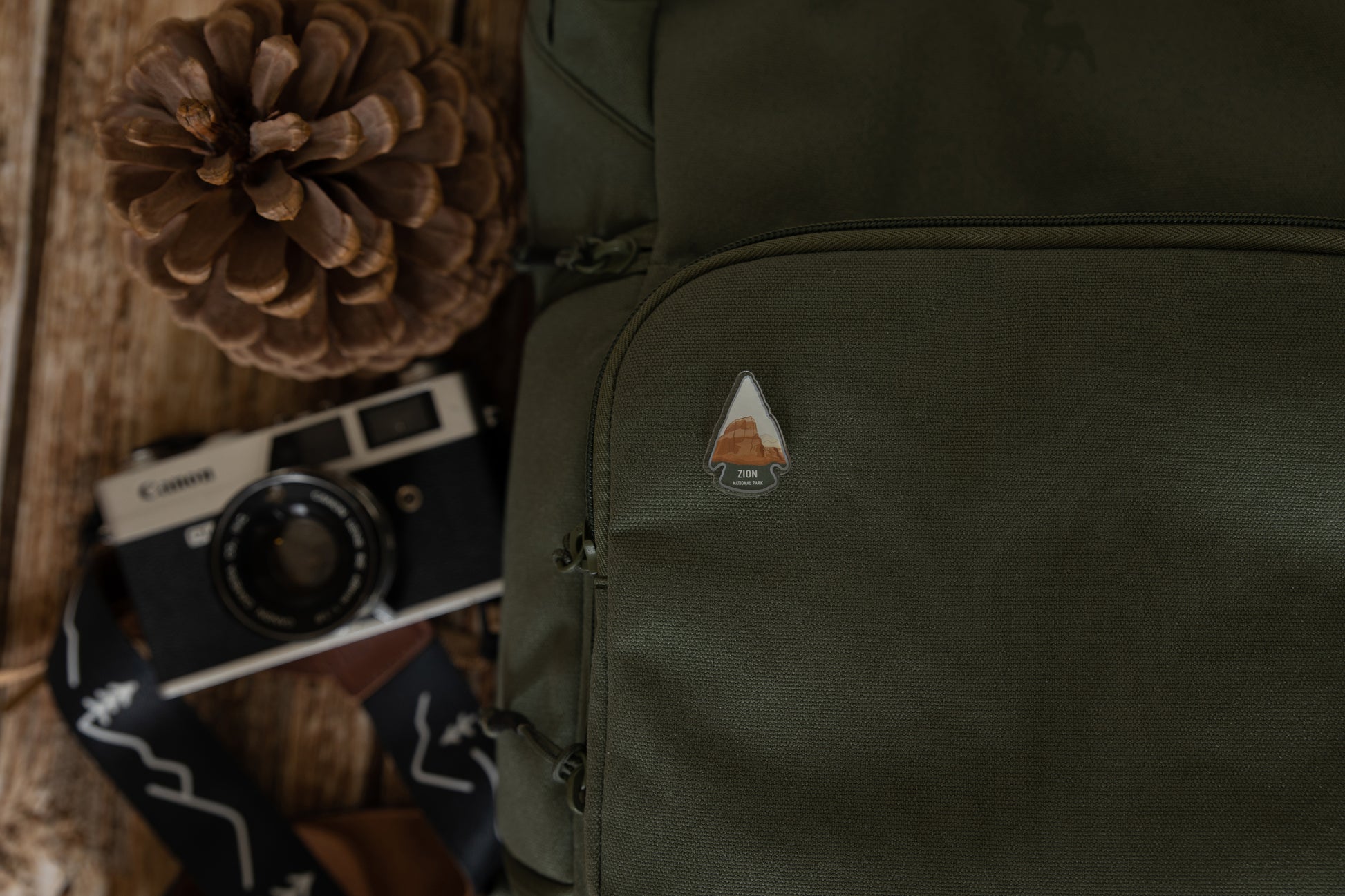 Zion National Park pin in shape of arrow head pinned on backpack